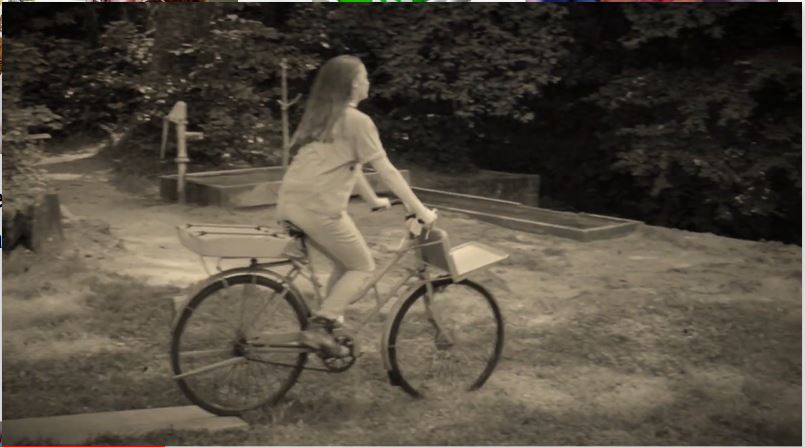 Image en noir et blanc d'une jeune fille sur un vélo.